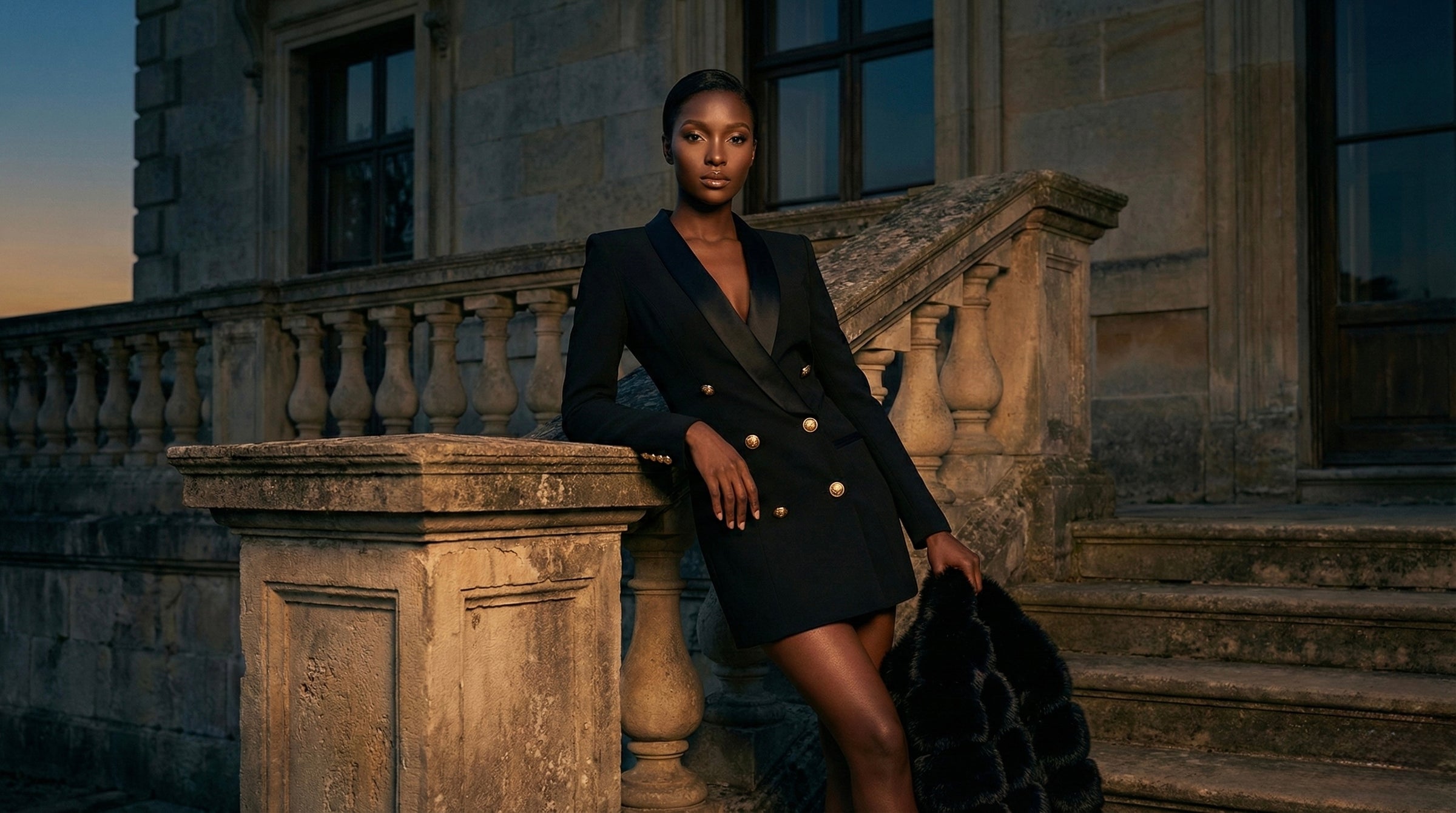 Woman in a black coat standing on stone steps with a building in the background