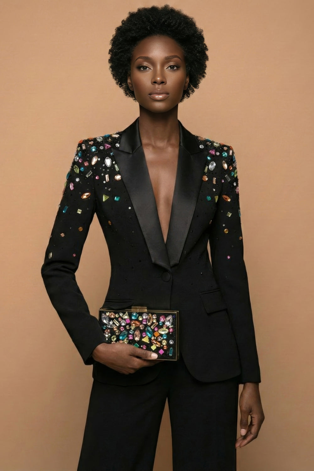 Woman wearing a black tuxedo with colorful embellishments against a beige background