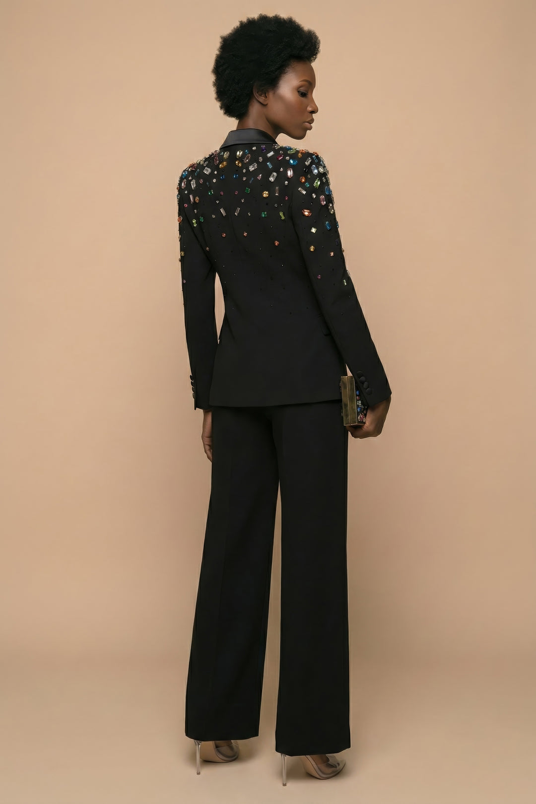 Woman wearing a black suit with colorful embellishments on a beige background