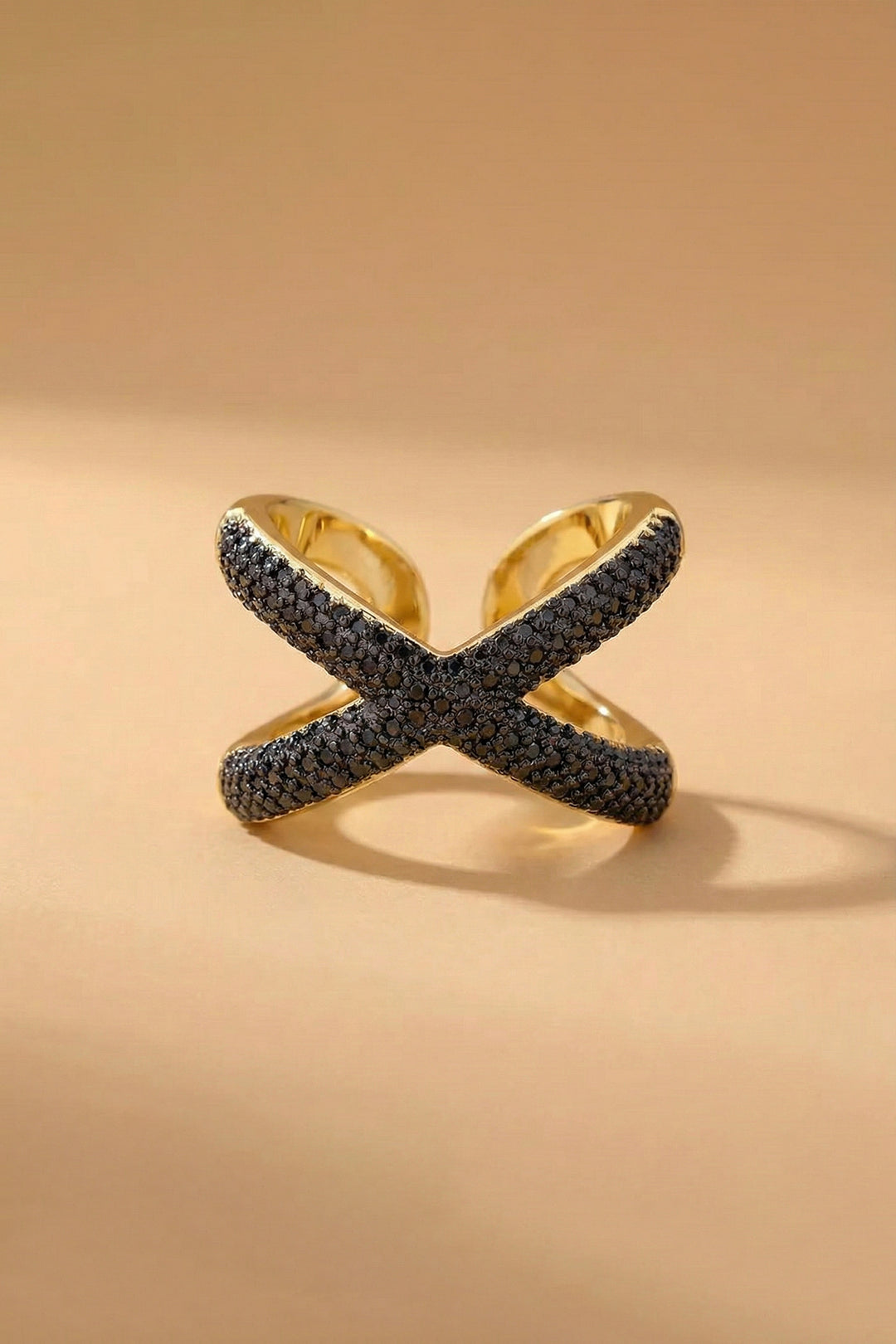 Gold ring with black gemstones on a beige background