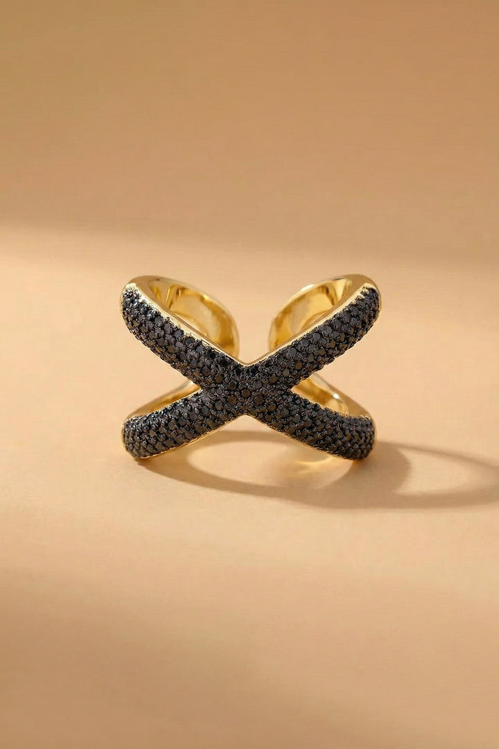 Gold ring with black gemstones on a beige background